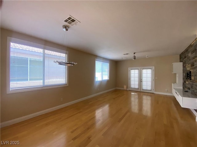 5376 S Conquistador St, Las Vegas, NV 89148 - unfurnished living room with baseboards, light wood-style flooring, french doors, and a fireplace