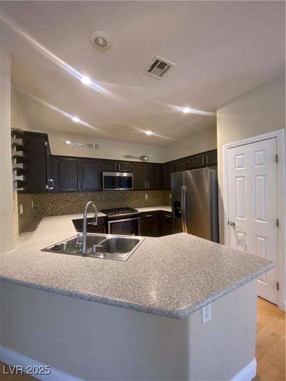 5376 S Conquistador St, Las Vegas, NV 89148 - kitchen with appliances with stainless steel finishes, a sink, a peninsula, backsplash, and light countertops