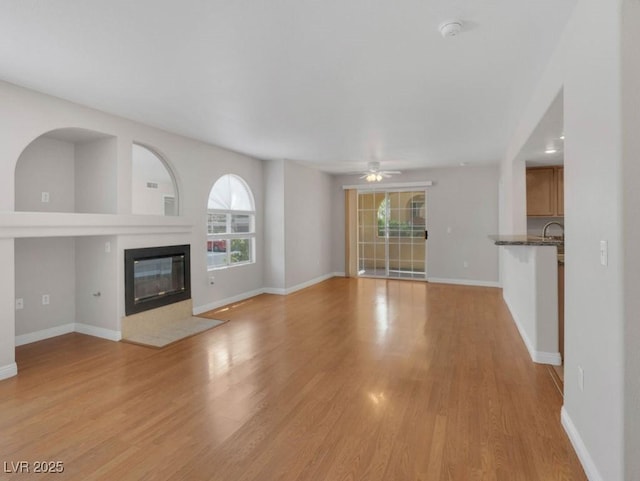 7950 W Flamingo Rd Unit 1077, Las Vegas, NV 89147 - unfurnished living room with a ceiling fan, light wood-type flooring, a fireplace with flush hearth, baseboards, and a sink