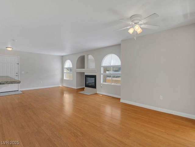 7950 W Flamingo Rd Unit 1077, Las Vegas, NV 89147 - unfurnished living room with light wood-type flooring, baseboards, a fireplace with flush hearth, and a ceiling fan
