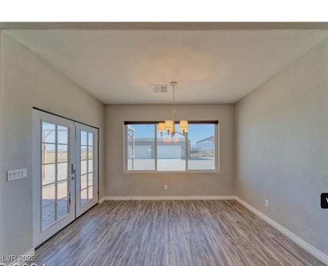 3791 Soplo Rd, Pahrump, NV 89048 - unfurnished dining area featuring wood finished floors, a chandelier, baseboards, and french doors