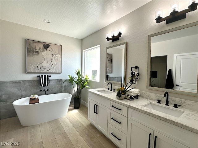 3791 Soplo Rd, Pahrump, NV 89048 - bathroom featuring wood finished floors, double vanity, a freestanding tub, and a textured ceiling
