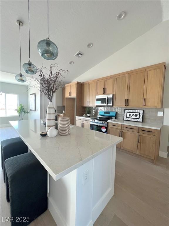 3791 Soplo Rd, Pahrump, NV 89048 - kitchen with stainless steel appliances, backsplash, vaulted ceiling, light stone counters, and a large island