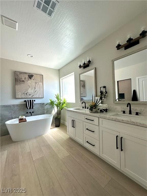 3791 Soplo Rd, Pahrump, NV 89048 - full bath with double vanity, a freestanding tub, wood finished floors, and a textured ceiling