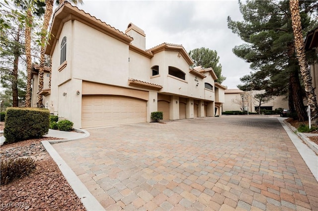 2050 W Warm Springs Rd Unit 4322, Henderson, NV 89014 - view of front facade with a chimney, stucco siding, decorative driveway, a tile roof, and an attached garage