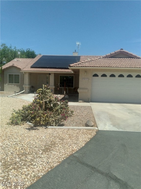 1611 Red Rock Dr, Pahrump, NV 89048 - view of front of home with a tiled roof, roof mounted solar panels, driveway, stucco siding, and an attached garage