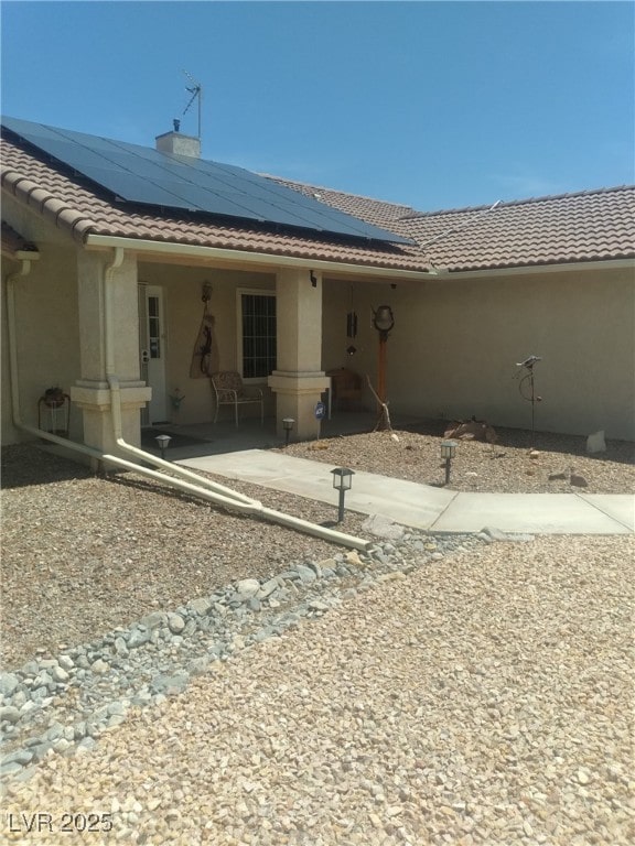 1611 Red Rock Dr, Pahrump, NV 89048 - view of front of home with a tile roof, solar panels, stucco siding, and a chimney