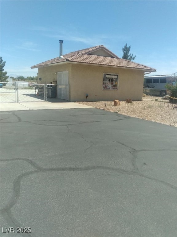 1611 Red Rock Dr, Pahrump, NV 89048 - view of property exterior featuring a gate, a tiled roof, and stucco siding
