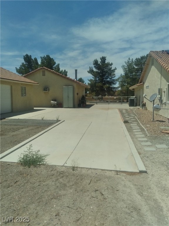 1611 Red Rock Dr, Pahrump, NV 89048 - view of side of home with stucco siding, a patio area, a tile roof, and central air condition unit