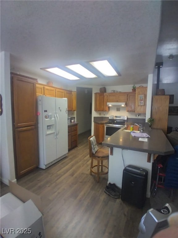 1611 Red Rock Dr, Pahrump, NV 89048 - kitchen featuring white fridge with ice dispenser, stainless steel range with electric cooktop, wood finished floors, a peninsula, and under cabinet range hood
