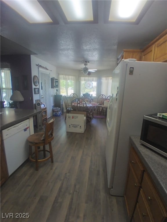 1611 Red Rock Dr, Pahrump, NV 89048 - kitchen with white dishwasher, stainless steel microwave, dark wood-style flooring, dark countertops, and a ceiling fan