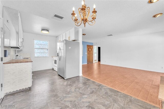 3158 La Luna Cir, Henderson, NV 89014 - kitchen featuring stainless steel fridge with ice dispenser, a chandelier, a textured ceiling, white cabinets, and light countertops