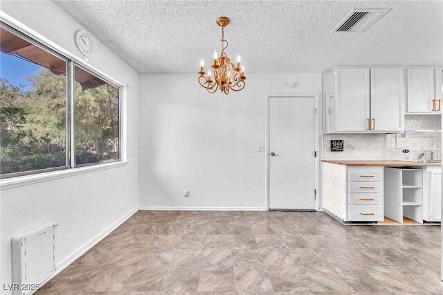 3158 La Luna Cir, Henderson, NV 89014 - kitchen with a chandelier, white cabinetry, a textured ceiling, decorative light fixtures, and tasteful backsplash