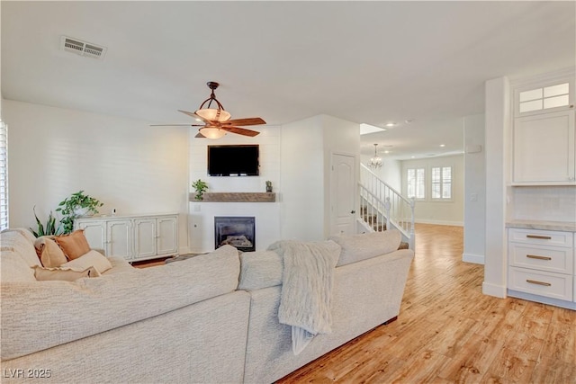5434 Fawn Chase Way, Las Vegas, NV 89135 - living area with stairway, baseboards, ceiling fan, a glass covered fireplace, and light wood-style flooring