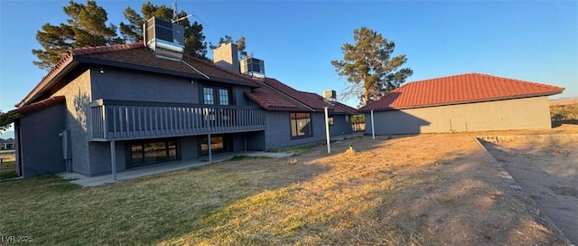 1967 N Moapa Valley Blvd, Logandale, NV 89021 - back of house with a wooden deck, stucco siding, a yard, a chimney, and a tile roof