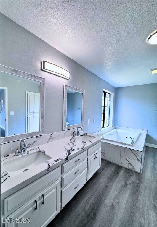 1967 N Moapa Valley Blvd, Logandale, NV 89021 - bathroom featuring a textured ceiling, wood finished floors, double vanity, and a bath