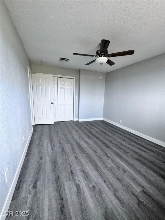 1967 N Moapa Valley Blvd, Logandale, NV 89021 - unfurnished bedroom featuring dark wood-type flooring, a textured ceiling, a closet, and a ceiling fan