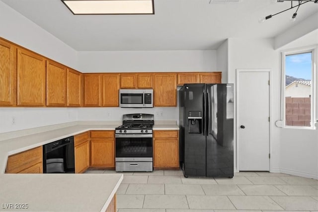 10642 Dawns Mist Ave, Las Vegas, NV 89129 - kitchen with black appliances, brown cabinetry, light countertops, and light tile patterned floors