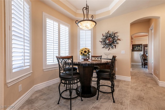 7718 Willow Cove Cir, Las Vegas, NV 89129 - dining space with arched walkways, ornamental molding, a raised ceiling, and baseboards