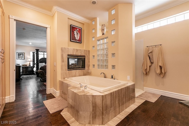 7718 Willow Cove Cir, Las Vegas, NV 89129 - full bathroom featuring a garden tub, crown molding, wood-type flooring, a tile fireplace, and baseboards