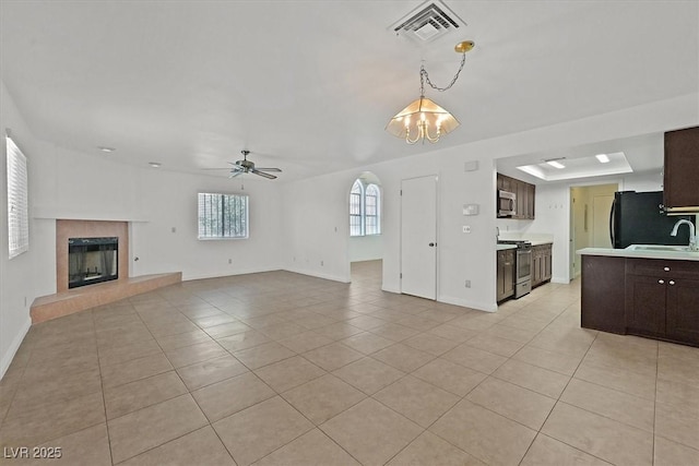 3935 Tirana Way, Las Vegas, NV 89103 - unfurnished living room featuring a chandelier, light tile patterned floors, a premium fireplace, a ceiling fan, and a sink