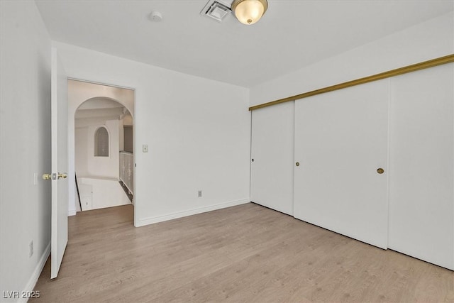 3935 Tirana Way, Las Vegas, NV 89103 - unfurnished bedroom with arched walkways, wood finished floors, a closet, and baseboards