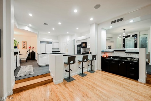 2231 S Tioga Way, Las Vegas, NV 89117 - kitchen featuring a peninsula, dark countertops, light wood finished floors, white cabinets, and dark cabinetry