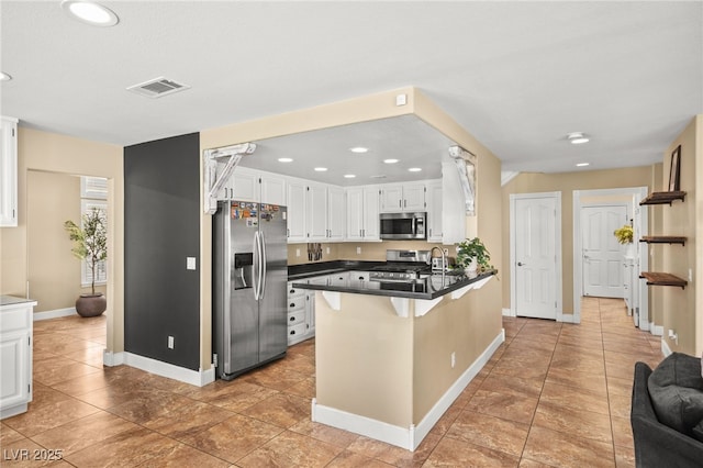 2021 Summit Pointe Dr, Las Vegas, NV 89117 - kitchen with appliances with stainless steel finishes, dark countertops, a peninsula, white cabinetry, and baseboards