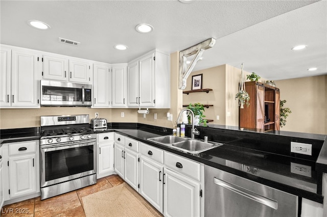 2021 Summit Pointe Dr, Las Vegas, NV 89117 - kitchen featuring stainless steel appliances, a sink, dark countertops, white cabinets, and a peninsula