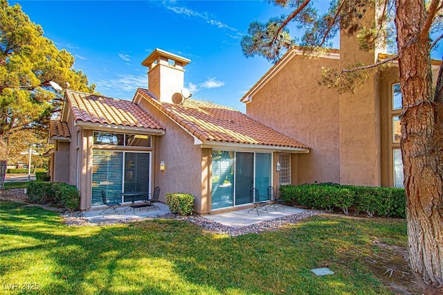 4911 Mount Pleasant Ln, Las Vegas, NV 89113 - rear view of house with a chimney, a patio, stucco siding, a lawn, and a tile roof