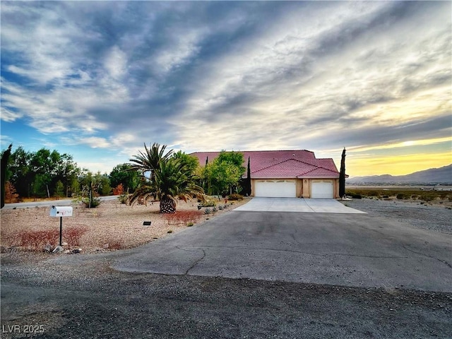 2780 Ave Of The Stars, Pahrump, NV 89060 - view of property hidden behind natural elements featuring concrete driveway, a garage, a tiled roof, and stucco siding