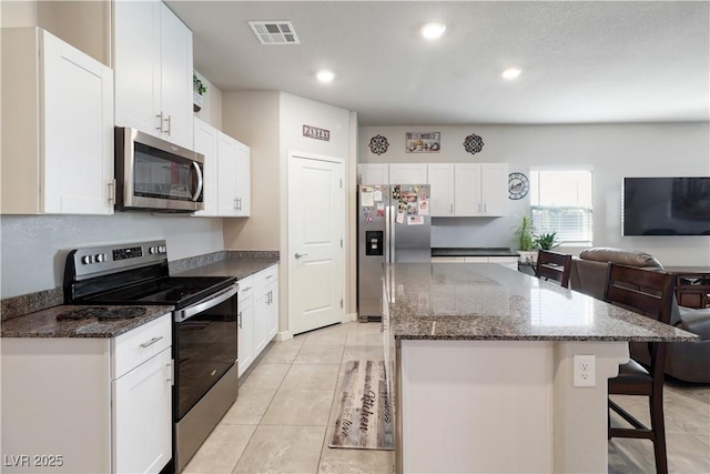 42 Late Harvest Ave, Pahrump, NV 89060 - kitchen featuring stainless steel appliances, a kitchen island, a breakfast bar area, white cabinetry, and dark stone counters
