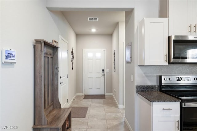 42 Late Harvest Ave, Pahrump, NV 89060 - kitchen with stainless steel appliances, white cabinetry, baseboards, light tile patterned floors, and dark stone counters