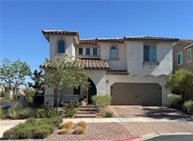 242 Homeward Way, Henderson, NV 89011 - mediterranean / spanish house featuring a tile roof, stucco siding, a garage, and decorative driveway