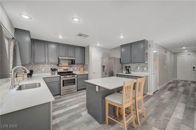 687 Porchtown Ave, Las Vegas, NV 89183 - kitchen with stainless steel appliances, a sink, gray cabinetry, decorative backsplash, and a kitchen island