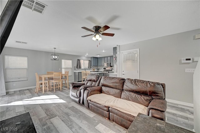 687 Porchtown Ave, Las Vegas, NV 89183 - living area featuring a ceiling fan, light wood-style flooring, baseboards, and a chandelier