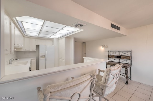 3111 Bel Air Dr Unit 23A, Las Vegas, NV 89109 - kitchen featuring white fridge with ice dispenser, a sink, light tile patterned flooring, light countertops, and a peninsula