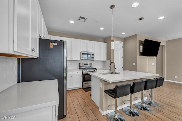 688 Monroe Hill Pl, Henderson, NV 89011 - kitchen featuring stainless steel appliances, a sink, light wood-type flooring, tasteful backsplash, and white cabinets
