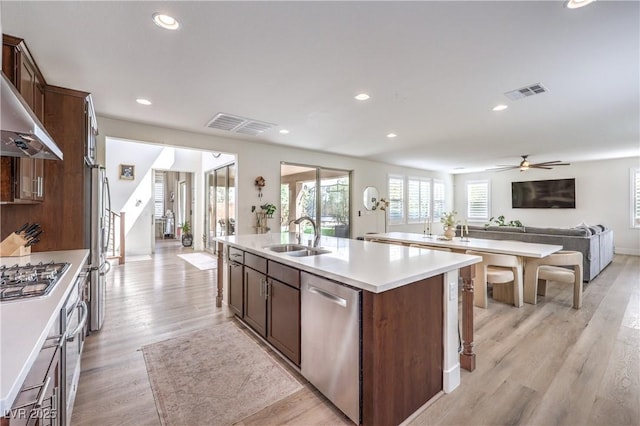 9655 Skye Star Ave, Las Vegas, NV 89166 - kitchen featuring stainless steel appliances, a sink, a kitchen island with sink, open floor plan, and light wood-style floors