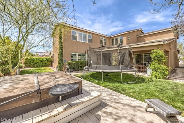 9655 Skye Star Ave, Las Vegas, NV 89166 - rear view of property featuring a trampoline, a wooden deck, stucco siding, a lawn, and a hot tub