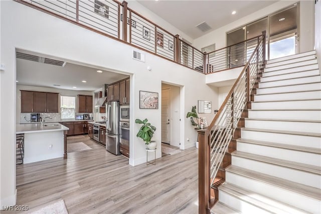 9655 Skye Star Ave, Las Vegas, NV 89166 - stairs featuring wood finished floors, a towering ceiling, recessed lighting, and baseboards