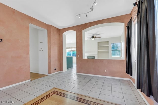 8849 Pheasant Valley Way, Las Vegas, NV 89123 - spare room with arched walkways, a ceiling fan, light tile patterned floors, built in shelves, and baseboards