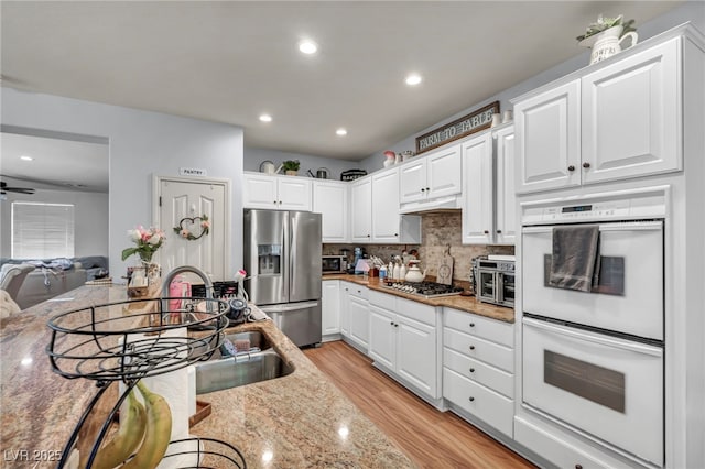 10213 Treasure Mountain Ct, Las Vegas, NV 89129 - kitchen with stainless steel appliances, light wood-type flooring, white cabinets, backsplash, and recessed lighting