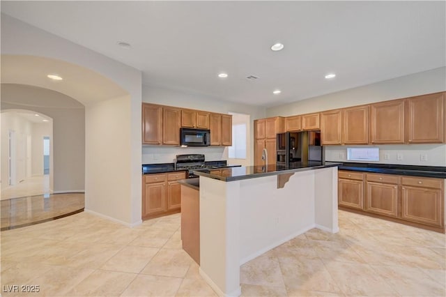 11441 Drappo Ave, Las Vegas, NV 89138 - kitchen with black appliances, arched walkways, recessed lighting, dark countertops, and an island with sink