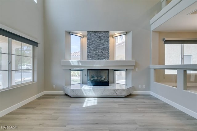 10908 Royal Highlands St, Las Vegas, NV 89141 - unfurnished living room with a towering ceiling, wood finished floors, baseboards, and a high end fireplace