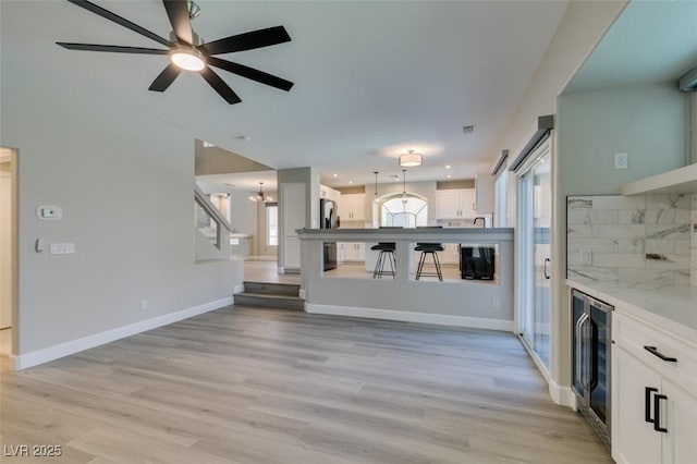 10908 Royal Highlands St, Las Vegas, NV 89141 - unfurnished living room with beverage cooler, a ceiling fan, light wood-style floors, baseboards, and recessed lighting