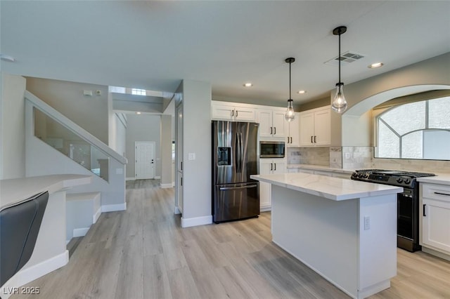 10908 Royal Highlands St, Las Vegas, NV 89141 - kitchen with stainless steel appliances, white cabinets, light wood-style floors, decorative backsplash, and recessed lighting