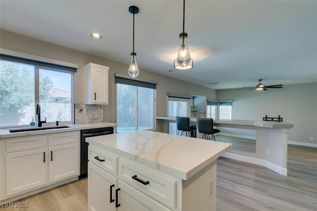 10908 Royal Highlands St, Las Vegas, NV 89141 - kitchen with a sink, dishwashing machine, a center island, light wood-style floors, and backsplash