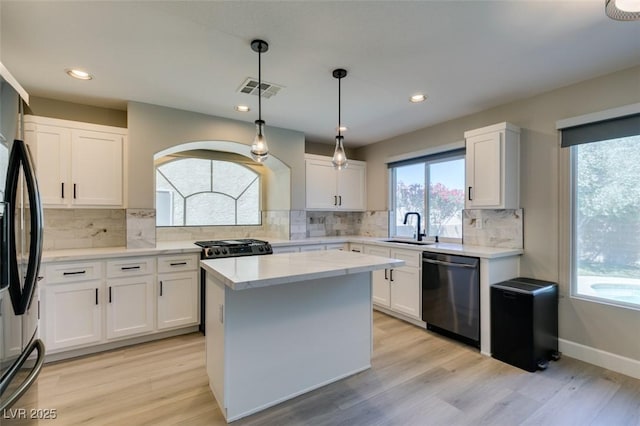 10908 Royal Highlands St, Las Vegas, NV 89141 - kitchen with appliances with stainless steel finishes, a sink, white cabinets, light wood-style flooring, and backsplash