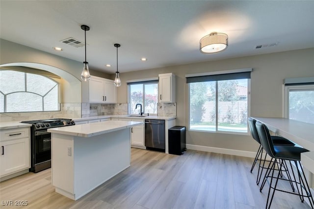 10908 Royal Highlands St, Las Vegas, NV 89141 - kitchen with range with gas cooktop, dishwasher, white cabinets, light wood finished floors, and tasteful backsplash